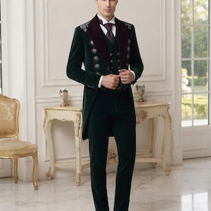 May include: A dark green velvet tailcoat suit featuring a deep burgundy velvet lapel, silver-toned decorative buttons, and intricate silver embroidery on the shoulders. The ensemble includes a matching vest, a white collared shirt, and a dark tie.