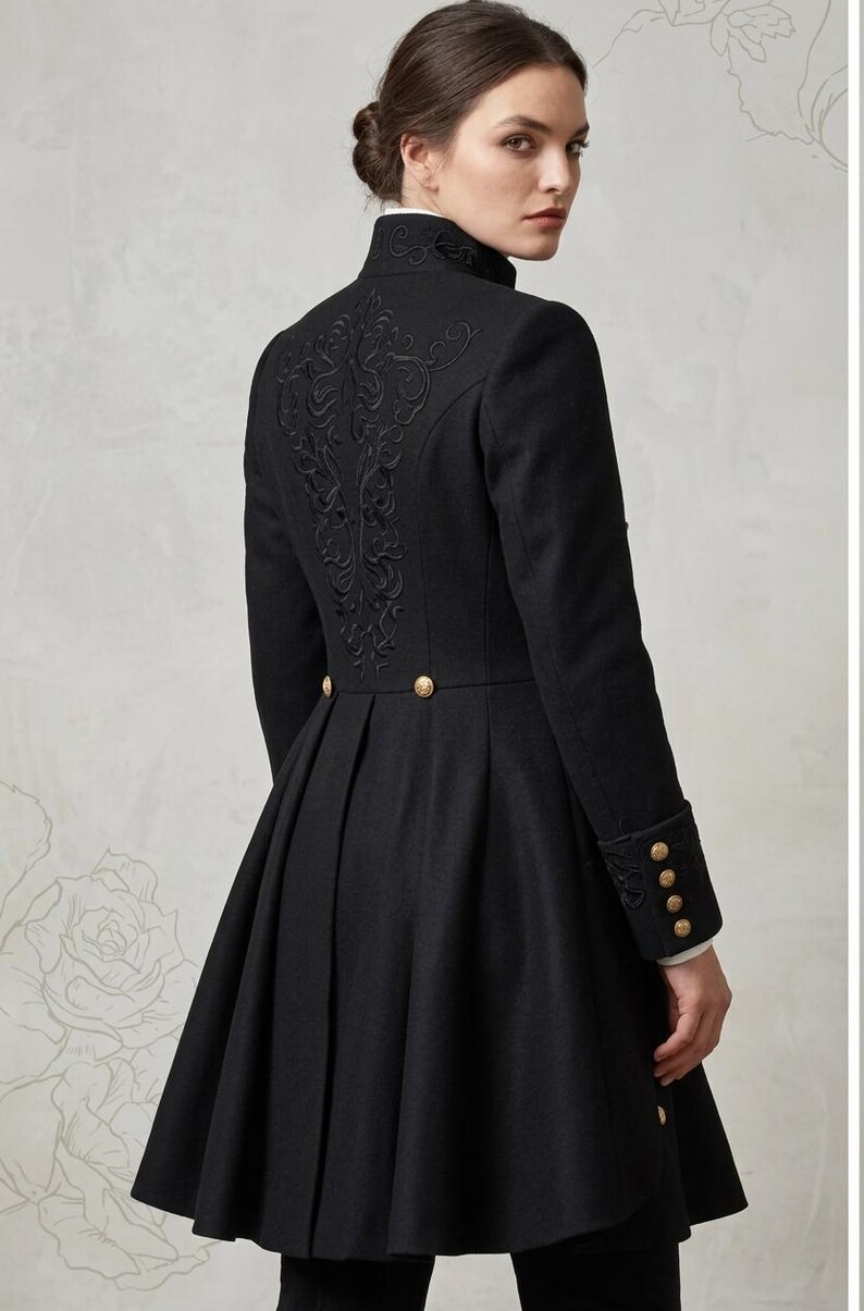 May include: A black coat featuring a high collar, long sleeves with four gold buttons on each cuff, and a pleated skirt. The back of the coat is decorated with intricate black embroidery and two gold buttons at the waistline.