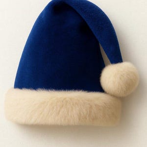 May include: A deep blue conical hat with a soft, velvety texture. The base features a wide, thick band of cream-colored faux fur trim, and the pointed top is finished with a matching cream-colored faux fur pom-pom hanging to the side.