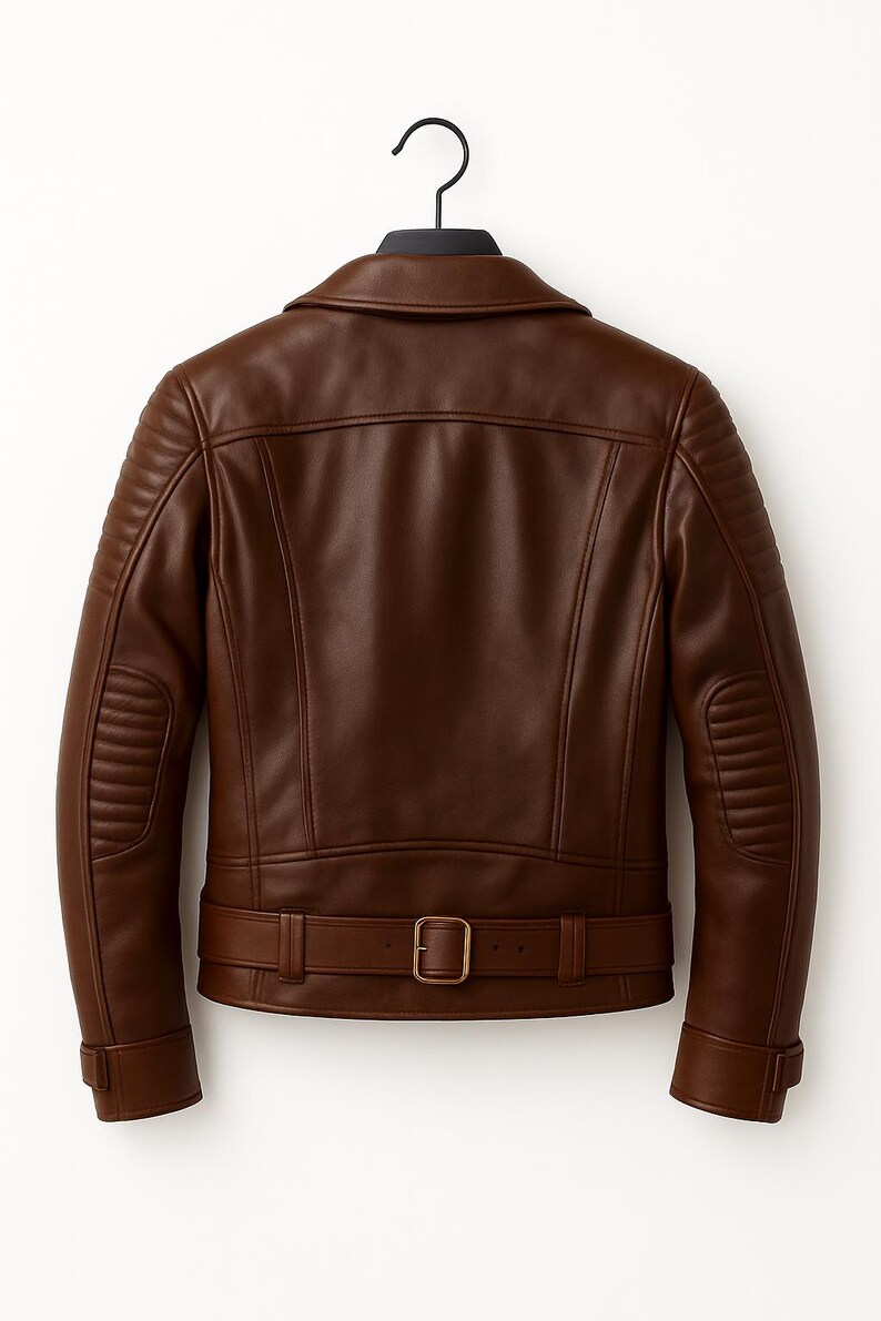 Puede incluir: Chaqueta de cuero marr&oacute;n con un dise&ntilde;o cl&aacute;sico, con cuello con solapas, acolchado en hombros y codos, y cintur&oacute;n en la cintura. La chaqueta est&aacute; colgada de una percha negra sobre un fondo blanco.