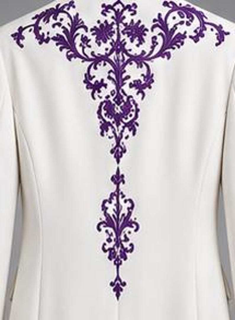 May include: A white blazer featuring a prominent, intricate purple embroidery design centered on the back. The embroidery displays a detailed, symmetrical scrollwork pattern that extends vertically from the shoulder area down the center back.