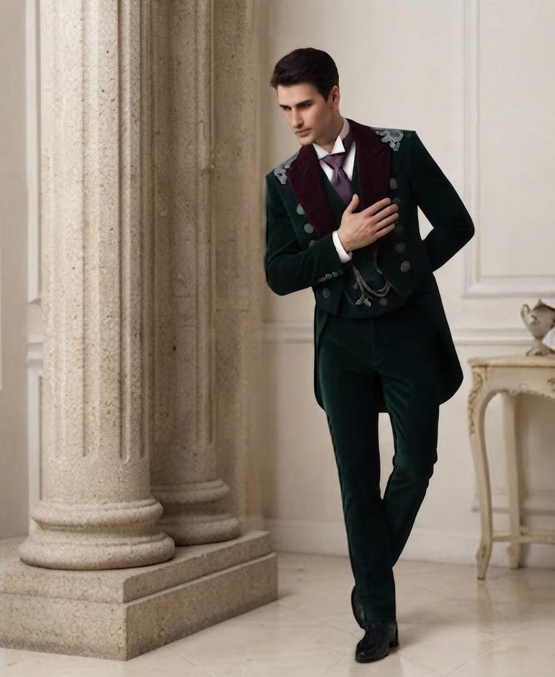 May include: A dark green velvet tailcoat suit featuring a deep burgundy velvet lapel, silver-toned buttons, and intricate silver embroidery on the shoulders. The ensemble includes a white collared shirt, a purple necktie, and a matching velvet vest.