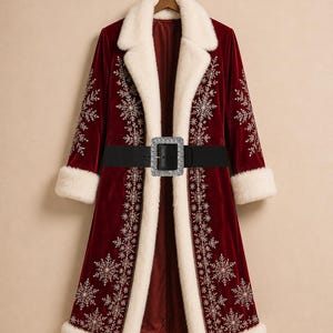 May include: A long, deep red velvet coat featuring white faux fur trim on the collar, cuffs, and front edges. The coat is decorated with intricate silver snowflake embroidery and includes a wide black belt with a large, rectangular crystal buckle.
