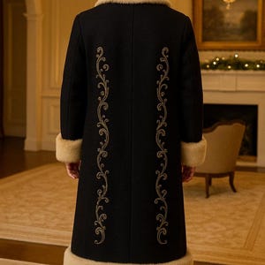 May include: A long black coat featuring a beige faux fur collar, cuffs, and hem. The back of the coat is decorated with two vertical rows of intricate gold embroidery in a swirling scroll pattern that runs from the shoulders to the lower hem.