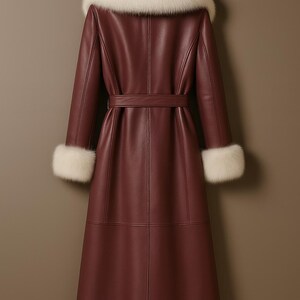 Pu&ograve; includere: Un lungo cappotto in pelle bordeaux con collo e polsini in pelliccia bianca, appeso a una gruccia di legno. Il cappotto ha una cintura in vita e cuciture dettagliate. I materiali lussuosi suggeriscono un capo di alta moda.