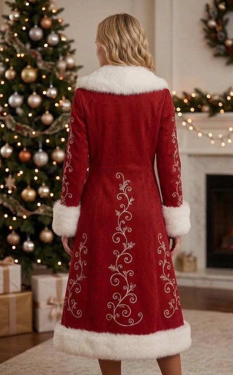 May include: A long red coat featuring white faux fur trim on the collar, cuffs, and hem. The back of the coat is decorated with intricate white swirling floral embroidery that runs vertically down the center and along the sleeves.