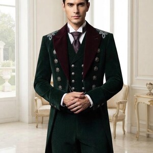 May include: A dark green velvet tailcoat suit featuring a deep burgundy velvet lapel, silver decorative buttons, and silver embroidery on the shoulders. The ensemble includes a matching vest, a white collared shirt, and a patterned dark purple necktie.