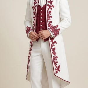 May include: A white long-coat suit featuring deep red floral embroidery along the lapels, cuffs, and pant hems. The ensemble includes a white collared shirt, a white cravat with a central pin, a deep red textured vest with white buttons, and white shoes.