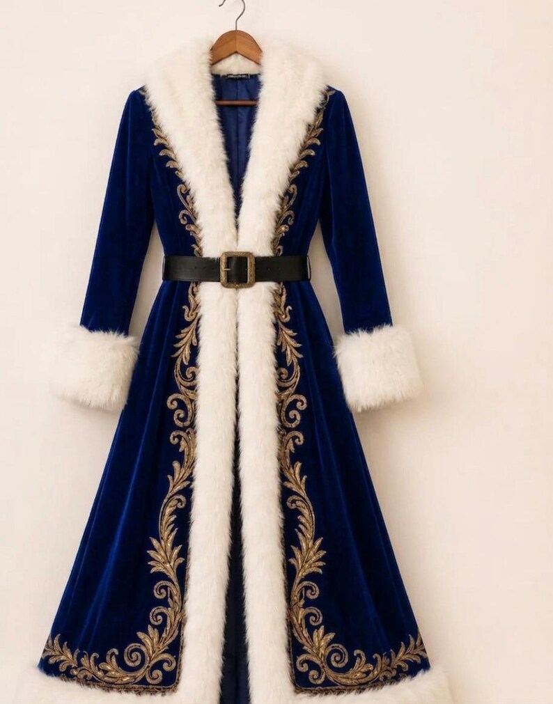 May include: A long, royal blue velvet coat featuring a thick white faux fur trim along the collar, cuffs, and hem. The coat is adorned with intricate gold embroidery along the front panels and is cinched at the waist with a black belt.