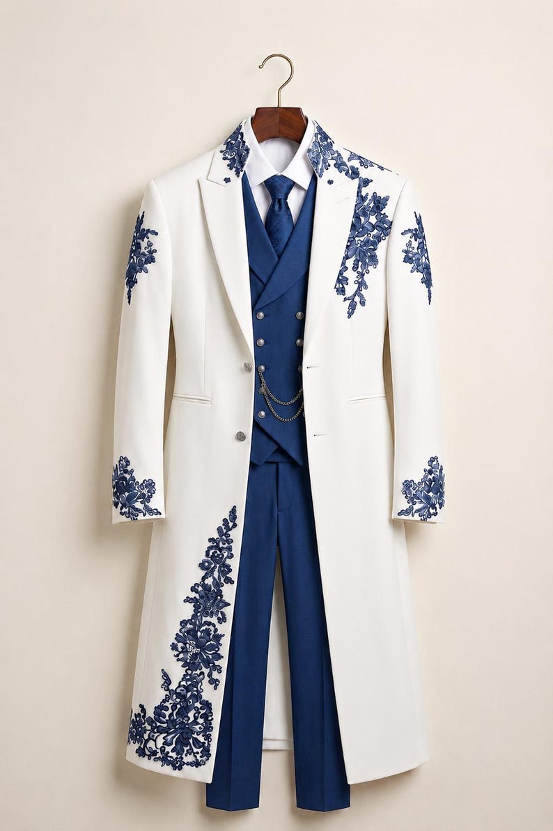 May include: A white long coat featuring intricate blue floral embroidery on the lapels, sleeves, and lower front. The coat is paired with a blue vest, a white collared shirt, a blue necktie, and blue trousers, complete with a silver chain detail.