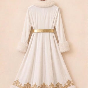May include: A long white coat featuring a faux fur collar and cuffs, a metallic gold belt at the waist, and a gold embroidered pattern along the bottom hem. The coat has long sleeves and a flared skirt, presented on a wooden hanger.