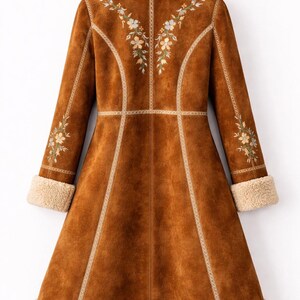 May include: A long brown coat featuring a cream-colored faux shearling collar, cuffs, and hem. The coat is decorated with floral embroidery on the upper back and sleeves, accented by light-colored vertical piping along the seams and a flared cut.