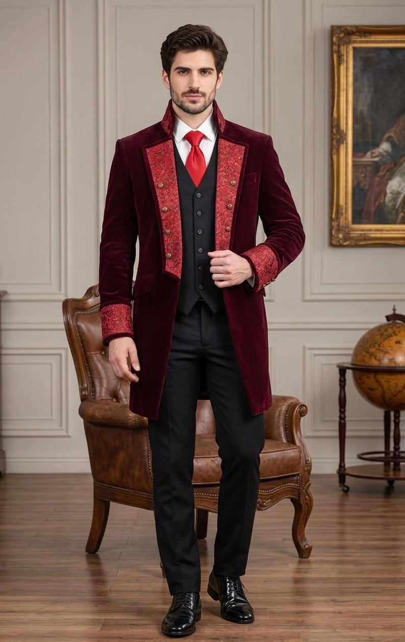 Puede incluir: Una levita de terciopelo burdeos con solapas y pu&ntilde;os de estampado rojo, sobre un chaleco negro, camisa blanca de cuello, corbata roja y pantal&oacute;n negro. El abrigo presenta botones de tono dorado en la parte delantera y un cuello alto.