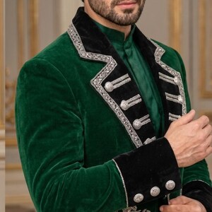 May include: A deep green velvet jacket featuring a black velvet lapel with silver metallic embroidery and silver buttons. The jacket includes a prominent silver embroidered griffin emblem on the lower front panel and matching black velvet cuffs.