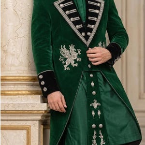 May include: A dark green velvet long coat featuring black velvet lapels and cuffs with silver embroidery. The coat includes a silver griffin emblem on the chest, silver buttons, and a matching green tunic underneath with silver floral embroidery.