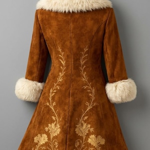 May include: A brown coat featuring a cream-colored faux fur collar and matching faux fur cuffs on the sleeves. The coat is decorated with gold-toned floral embroidery that extends from the hemline up the back panels in a vine-like pattern.