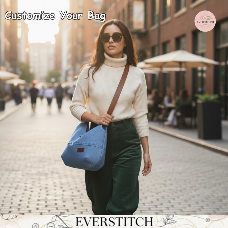 May include: A light blue denim hobo bag with a brown leather strap and a small rectangular brown patch on the front. The text "Customize Your Bag" appears in the top left corner, and the logo "EVERSTITCH" is at the bottom of the image.