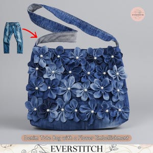 Può includere: Una borsa tote in denim con un abbellimento floreale. La borsa è realizzata in denim blu e decorata con numerosi fiori in denim, ciascuno centrato con una perla. Ha una lunga tracolla in denim e il testo "EVERSTITCH".