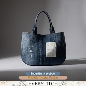 May include: A dark blue denim handbag with a distressed texture and two top handles. A white rectangular fabric label is stitched to the front, featuring the text "ULTRA HIGH-RISE BERMUDA 32 HAPPY NATURE" along with a small yellow flower graphic.