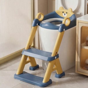 May include: A blue and yellow child's toilet step stool with a bear-shaped seat. The step stool has two steps and handles for support. The design is intended to help children reach the toilet.