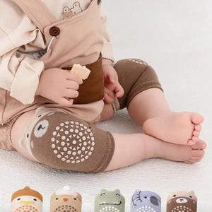 Può includere: Ginocchiere per bambini marroni con un design a orsetto e punti di presa bianchi. L'immagine mostra anche un bambino che indossa le ginocchiere e una selezione di calzini a tema animale con suole antiscivolo.