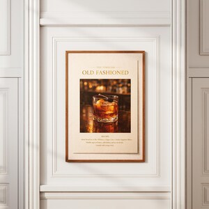 May include: A framed print featuring an Old Fashioned cocktail. The image shows a glass of the drink with an orange peel and cherry garnish. The print has text that reads "The Timeless Old Fashioned" in gold lettering.