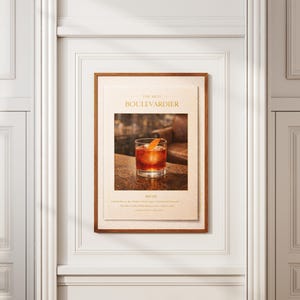 May include: A framed print featuring a cocktail, the "Boulevardier." The image shows a glass with a dark amber drink and an orange peel garnish. The print is in a wooden frame, mounted on a white wall.