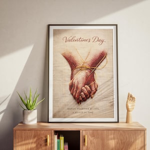 May include: Framed Valentine's Day art print showing clasped hands tied with twine. The print has the words "Valentine's Day" at the top and "Woven together by fate, a stitch in time" at the bottom. The art is displayed on a wooden cabinet.