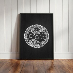 Könnte beinhalten: Ein schwarz gerahmter Kunstdruck mit einer weißen kreisförmigen Illustration auf schwarzem Hintergrund. Das Motiv zeigt eine zusammengerollte Schlange, die einen Ring bildet und himmlische Elemente wie Mondsicheln, Sterne und Wellenlinien umgibt.