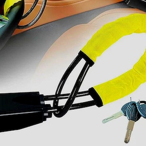 Pode incluir: Um bloqueio de volante de carro preto com uma capa protetora amarelo brilhante. O bloqueio está conectado a um cabo de metal preto e vem com três chaves. O fundo mostra um interior de carro.