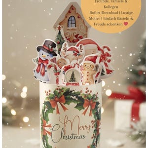 Op de afbeelding: Een witte cilindrische container met een kerstkransontwerp en de woorden "Merry Christmas". De container is gevuld met feestelijke papieren uitsparingen van een sneeuwpop, peperkoekmannetje en andere vakantiefiguren. Tekst op de afbeelding zegt "DIY Duplo-Banderolen - Perfektes Weihnachtsgeschenk".