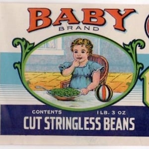 Op de afbeelding: Vintage voedseletiket voor Baby Brand Cut Stringless Beans. Het etiket toont illustraties van een kind en sperziebonen, met de tekst "Baby Brand" en "Cut Stringless Beans". De inhoud is 1 lb. 3 oz.