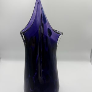 Cobolt blue/purple hand blown glass art piece with teardrop shape and pinched spire at the top.