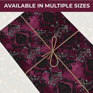 May include: A gift wrapped in burgundy paper with a black and white floral pattern, tied with a gold string. The text "AVAILABLE IN MULTIPLE SIZES" is at the top.