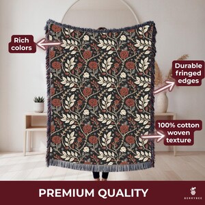 May include: A woven cotton throw blanket with a floral pattern of red roses and white leaves on a black background. The blanket has fringed edges and the words "Premium Quality" are at the bottom.