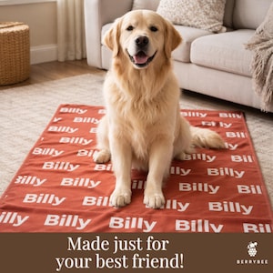 以下が含まれることがあります： ゴールデンレトリバーが、名前「Billy」が白で繰り返しプリントされた赤い犬用ブランケットの上に座っています。ブランケットはソファの前の明るい色のラグの上にあります。「Made just for your best friend!」というテキストが下にあります。