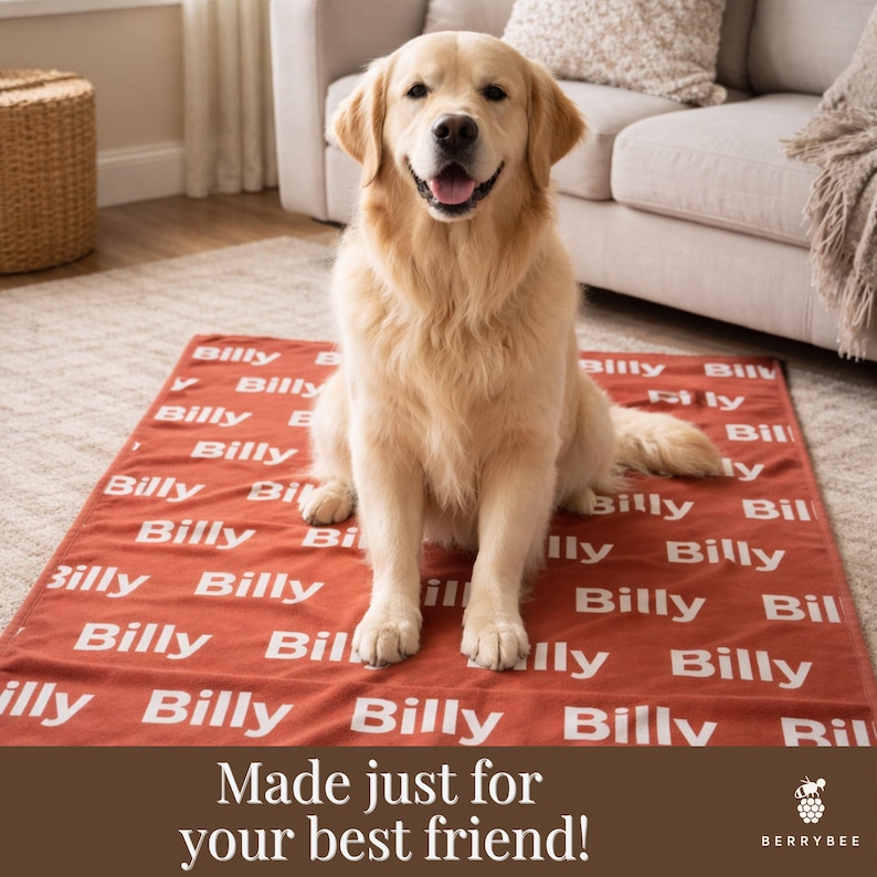 以下が含まれることがあります： ゴールデンレトリバーが、名前「Billy」が白で繰り返しプリントされた赤い犬用ブランケットの上に座っています。ブランケットはソファの前の明るい色のラグの上にあります。「Made just for your best friend!」というテキストが下にあります。