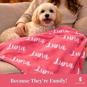 以下が含まれることがあります： 白い筆記体で「Luna」とプリントされたピンク色のブランケット。小さな薄い色の犬がブランケットの上にいます。「Because They're Family!」というテキストが下にあります。