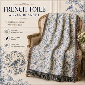K&ouml;nnte beinhalten: Eine French Toile gewebte Decke mit blauem und wei&szlig;em Blumen- und Vogelmuster, Fransen an den R&auml;ndern, drapiert &uuml;ber einem Stuhl. Der Text auf dem Bild lautet "French Toile Woven Blanket".