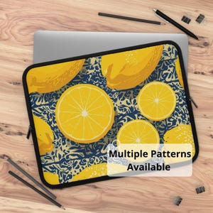May include: Laptop sleeve featuring a vibrant lemon pattern. The design includes large yellow lemon slices and whole lemons against a blue and cream background. The text "Multiple Patterns Available" is displayed on the sleeve.