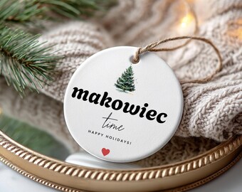 Könnte beinhalten: Ein weißer, runder Weihnachtsschmuck mit dem Schriftzug "makowiec time" in schwarzer Schrift, einem Aquarell-Weihnachtsbaum und einem roten Herz. Der Schmuck hängt an einer Schlaufe aus Naturfaser.