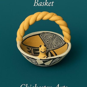 May include: Acoma Bird Effigy Basket with a yellow twisted handle. The ceramic basket features a yellow and black geometric design with a smiling bird effigy. The text "Chichester Arts" is at the bottom.
