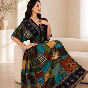 Puede incluir: Un vestido midi con diseño de patchwork y varios estampados en tonos azul marino, verde bosque, naranja óxido y beige. El vestido presenta un escote en V, mangas cortas y una cintura elástica fruncida con una falda amplia y fluida.