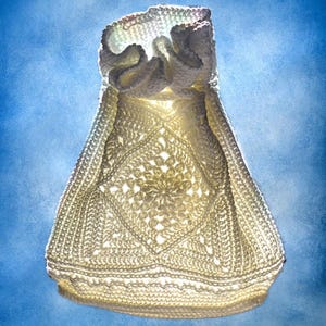 May include: A white crochet drawstring pouch featuring a central diamond-shaped motif with intricate openwork stitching. The bag has a gathered, ruffled top edge and a flat, rectangular base, constructed from off-white yarn with a textured finish.
