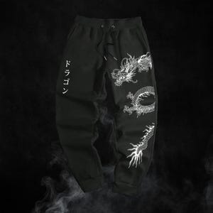 May include: Black sweatpants with a drawstring waist and a white dragon design. The Japanese word "dragon" is printed vertically on the left leg. The dragon graphic wraps around the right leg.