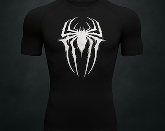 Puede incluir: Camiseta de compresión negra de manga corta con un emblema de araña blanco en el pecho. El diseño de la araña tiene una apariencia detallada y estilizada con líneas afiladas y un aspecto texturizado. La camiseta tiene cuello redondo y un diseño ajustado.