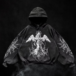 May include: Black hooded sweatshirt with a distressed finish. It features a white angel graphic on the front, complete with wings and a halo. White lightning bolt patterns adorn the sleeves. The sweatshirt has a front pocket and a drawstring hood.