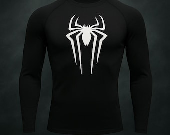 Puede incluir: Camiseta negra de manga larga con un emblema de araña blanco en el pecho. El emblema es una araña estilizada con líneas afiladas y angulares. La camiseta tiene cuello redondo y está hecha de un material liso, probablemente atlético.