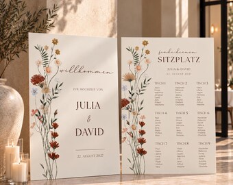 May include: Two rectangular wedding signs with a cream background and wildflower illustrations. The left sign reads willkommen ZUR HOCHZEIT VON JULIA & DAVID 22. AUGUST 2027. The right sign reads finde deinen SITZPLATZ JULIA & DAVID 22. AUGUST 2027.