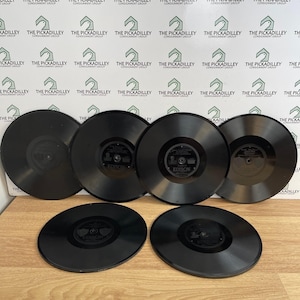 May include: Six black circular Edison phonograph records arranged in two rows. Each record features a central label with the Edison brand name and text details. The discs have a smooth, glossy finish and are positioned on a flat surface.